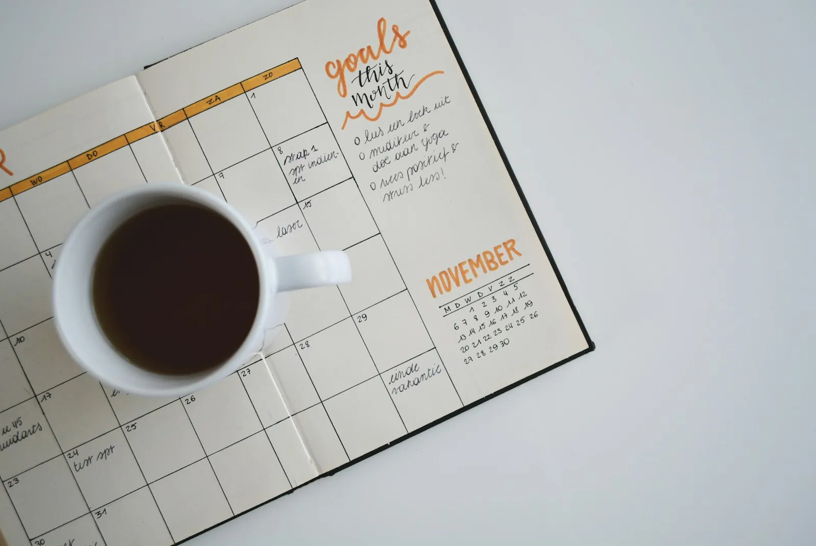 A monthly calendar and a cup of coffee on a desk